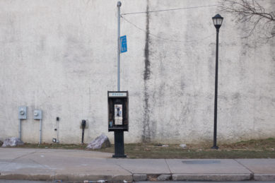 Pay telephone with lamp and wall in background in Darby Pennsylvania